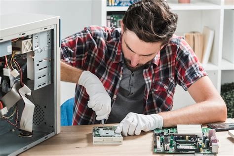 Young male technician wearing gloves fixing computer motherboard with ...