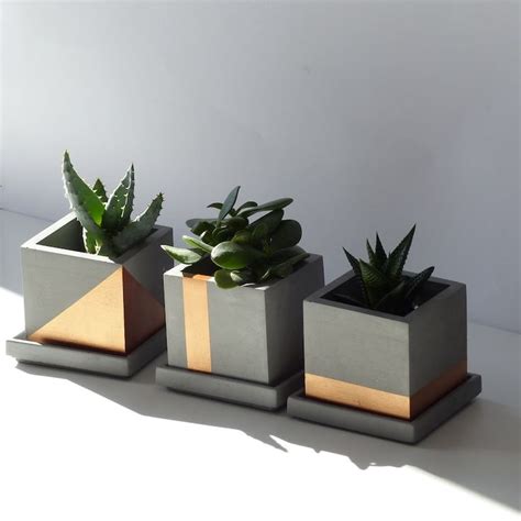 three cement planters with succulents in them on a white table top