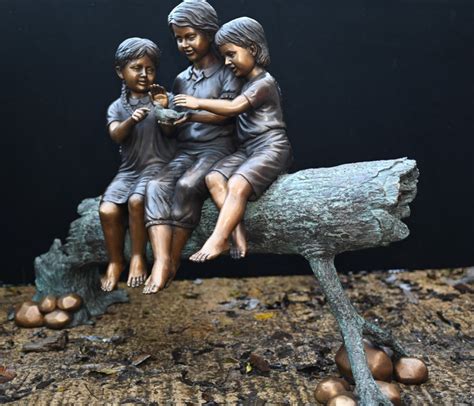 Colored outdoor statue of a child pressing their forehead on the hand of a seated elder