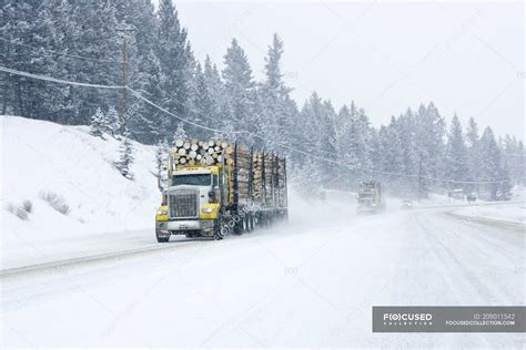 Logging trucks driving in winter storm on highway in British Columbia ...