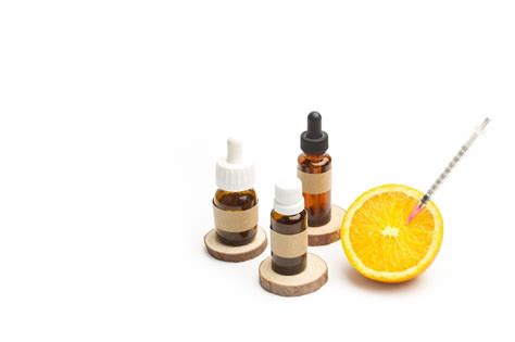 A half orange with a syringe stuck and medical bottles on a white ...