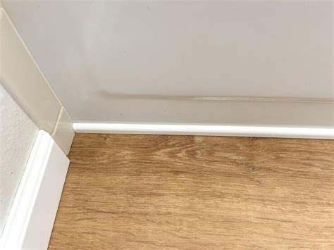 Installing white vinyl baseboards and trim pieces in a room under ...