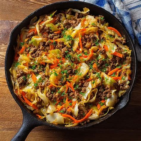 A skillet containing a dish with cooked cabbage ground meat and tomatoes resembling unstuffed cabbag
