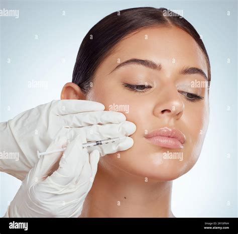 Closeup of woman getting lip fillers or botox. Young caucasian model isolated against a grey ...