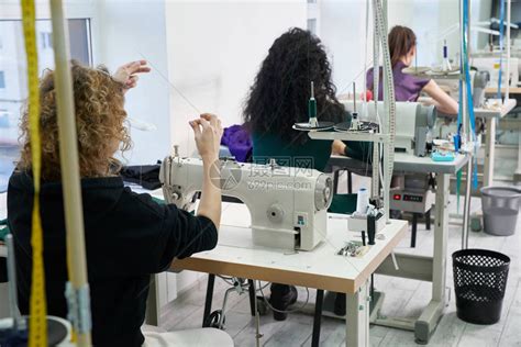 年轻的裁缝女人在缝纫机上缝制衣服微笑的女裁缝和她的手关闭在车间专注于高清图片下载-正版图片502576417-摄图网