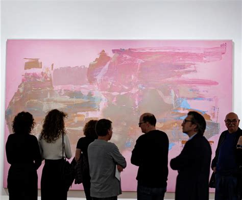Visitors stand in front of a large, vibrant abstract painting dominated ...
