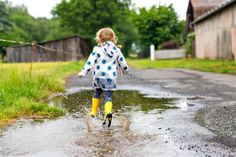 蹒跚学步的小女孩穿着黄色雨靴高清图片下载-正版图片506609321-摄图网