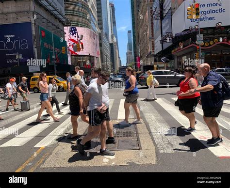 Pedestrians are surrounded by video billboards as they cross the street ...