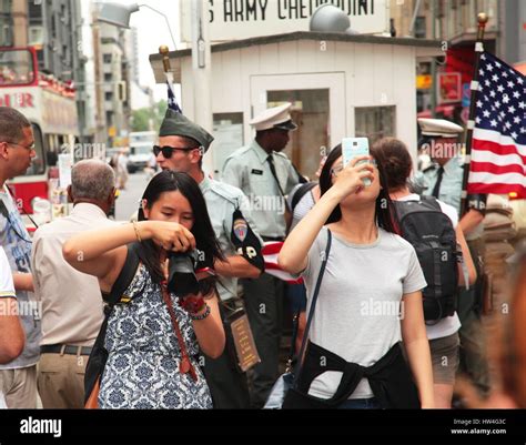 Two Asian tourists take photos at Checkpoint Charlie in central Berlin ...