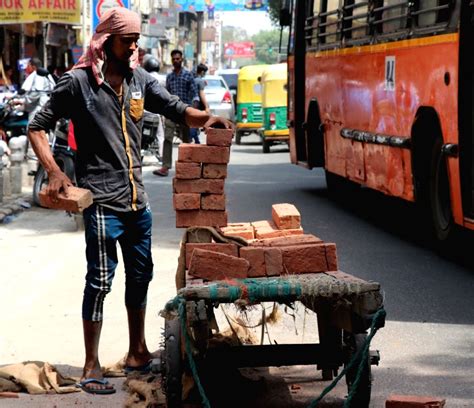 A labour loads bricks on a cart during his work o