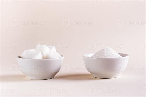 Sugar cubes and granulated sugar in bowls on a light background ...