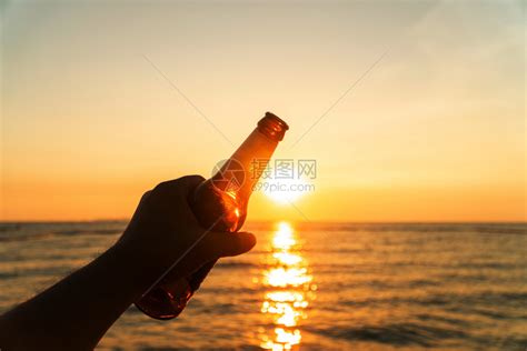 乐趣喝寒冷的人手握着啤酒瓶晚上把手举在天日落夏的海滩节日庆祝夏的沙滩高清图片下载-正版图片307827192-摄图网