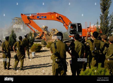 People watch an Israeli army bulldozer demolishing homes in the Palestinian urban refugee camp of Nu