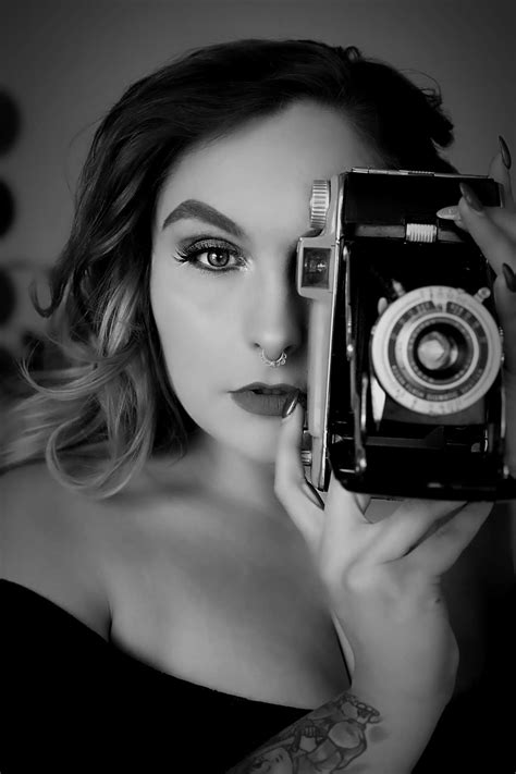 A black and white photo shoot of a woman holding a retro camera up to ...