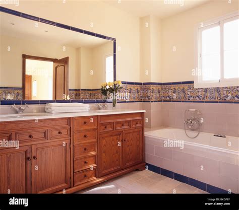 Large mirror above fitted wood vanity unit in modern Spanish bathroom ...