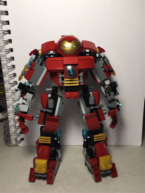 a red and yellow lego robot standing next to a spiral notebook