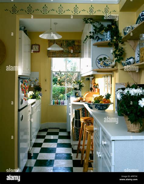 Black and white vinyl floor tiles in yellow galley kitchen with ...