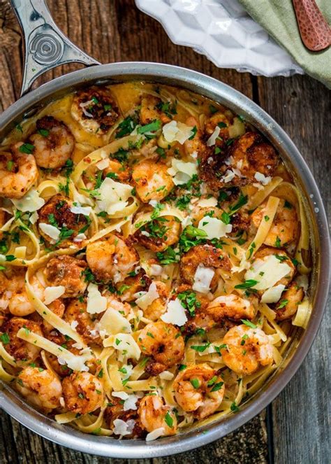 pasta with shrimp and parmesan cheese in a skillet on a wooden table