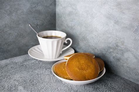 Pancakes in dish and coffee in porcelain cup on gray surface, white ...