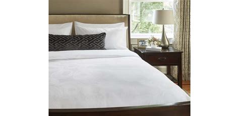 JW Marriott bed in hotel room with logo on an accent pillow