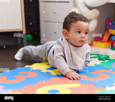 Adorable hispanic baby crawling on floor at kindergarten Stock Photo ...