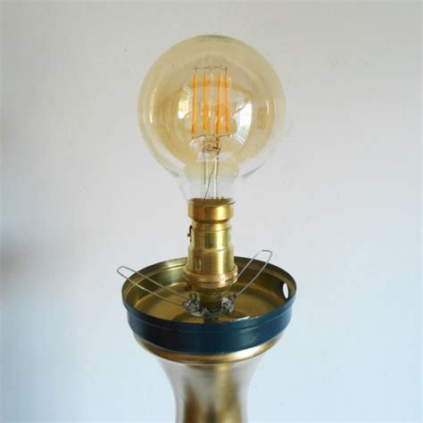 A gold and navy floor lamp with a vintage glass globe shade ...