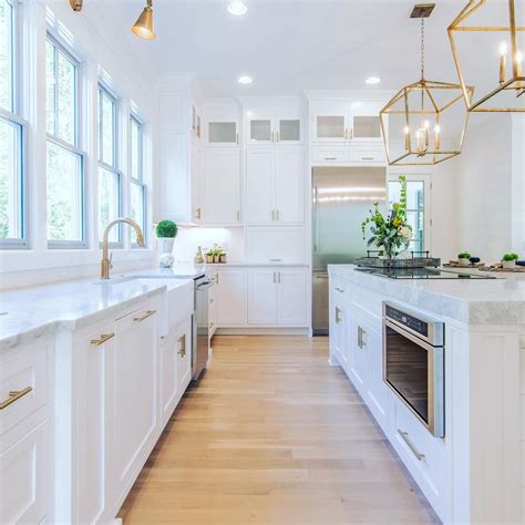 White Kitchen Design with Gold Accents and Pine Floors