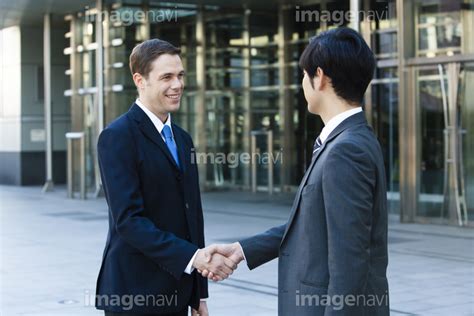 握手をする日本人ビジネスマンと外国人ビジネスマン - 商用利用可能な写真素材・イラスト素材ならストックフォトの定額制ペイレスイメージズ
