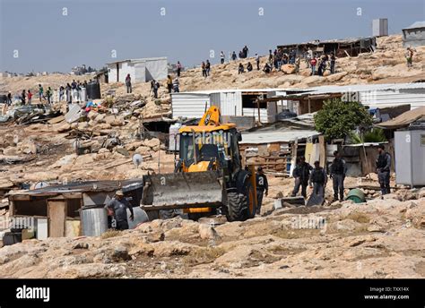 People watch an Israeli army bulldozer demolishing homes in the Palestinian urban refugee camp of Nu