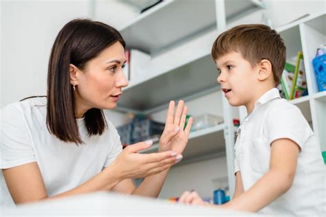 Beautiful woman speech therapist teaches boy the correct pronunciation ...