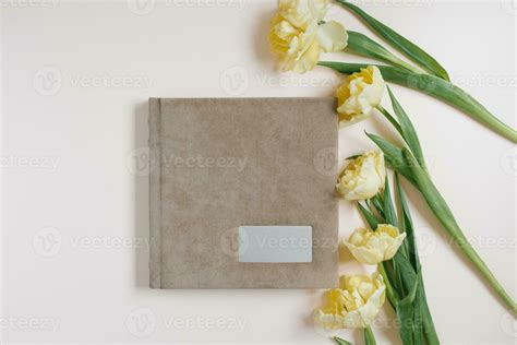 Beige family or wedding photo book and tulip flowers lie on a light ...