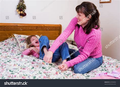 A Mother Tickling Her Elementary Daughter On A Big Bed. Stock Photo ...