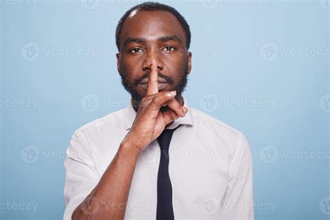 Portrait of african american male entrepreneur doing hush sign with ...