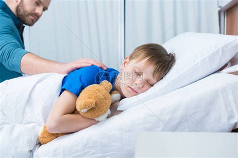 父亲抚摸着躺在医院病床上的生病的小儿子高清图片下载-正版图片502553296-摄图网