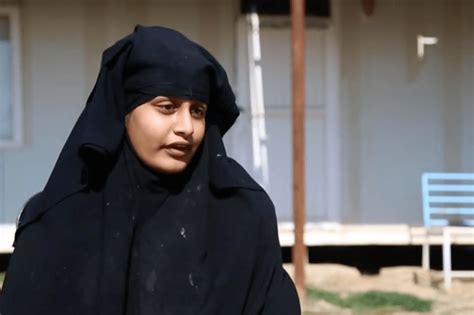 Shamima Begum leaning against a door frame. She has long dyed brown hair and is wearing sunglasses with a light grey top underneath a sweatshirt jacket