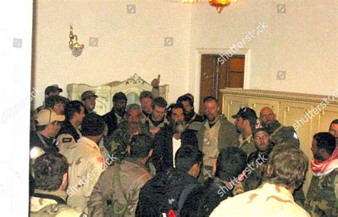 Black-and-white photo of Saddam Hussein, in a suit, with a group of women students