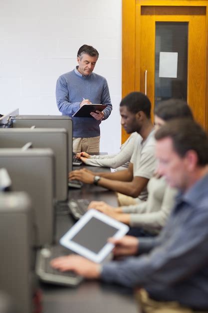 Teacher writing on clipboard in computer room | Premium Photo
