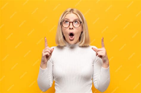 Premium Photo | Blonde woman feeling awed and open mouthed pointing ...