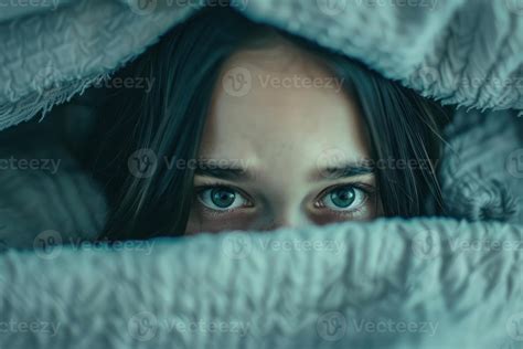 Intense close-up of a person's eyes peering out from under a textured ...