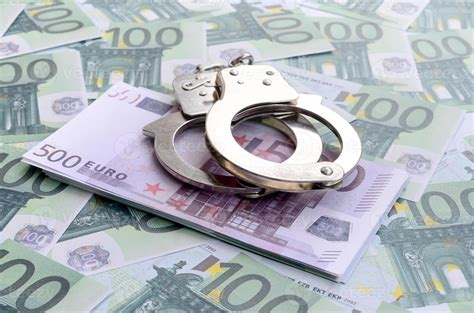 Police handcuffs lies on a set of green monetary denominations of 100 ...
