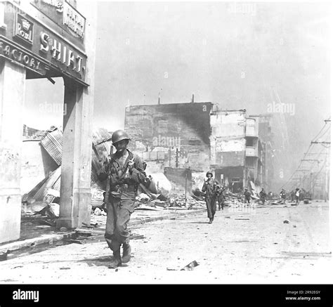 American troops move through the burned out business district of Manila ...