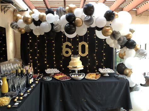 a black and gold 50th birthday party with balloon garlands, cake and ...