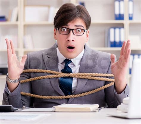 Businessman tied up with rope in office | Stock image | Colourbox