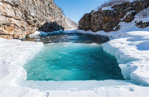 Stunning frozen waterfall and turquoise pool in snowy landscape ...