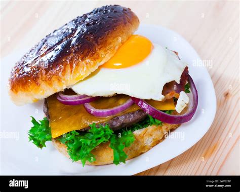Hamburger with fried egg, bacon, cheese, lettuce, onion Stock Photo - Alamy