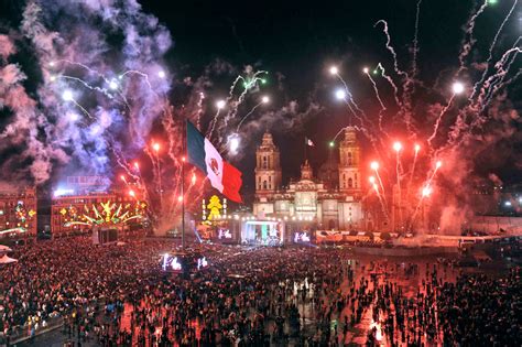 Zócalo lleno con fuegos artificiales y banderas.
