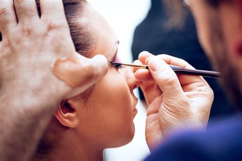 Close up of a makeup man artist getting eyeliner to model. | Premium Photo