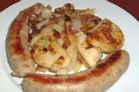A plate with pierogies sausages and cabbage served with a small bowl of sour cream