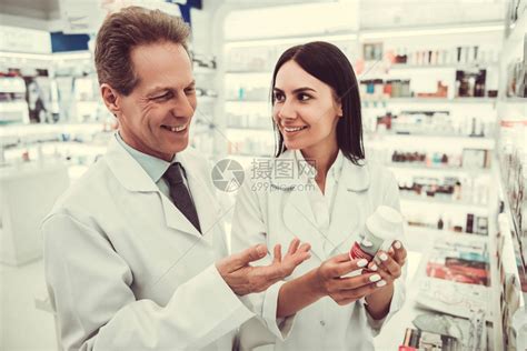 美药剂师在药店工作时讨论药物和微笑并高清图片下载-正版图片507372422-摄图网