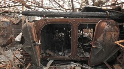 A man walks past a burnt armoured personnel carrier near buildings destroyed in the course of Ukrain